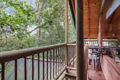 Balcón de madera con barandal con vista al exuberante jardín de Sukha Glamping en Ríonegro, Colombia