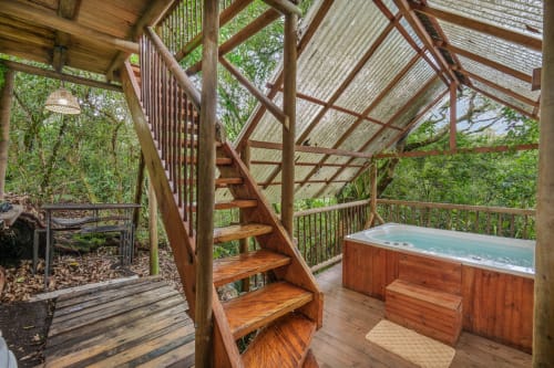 Terraza de madera con jacuzzi y escaleras en Sukha Glamping en Ríonegro, rodeada de exuberante jardín