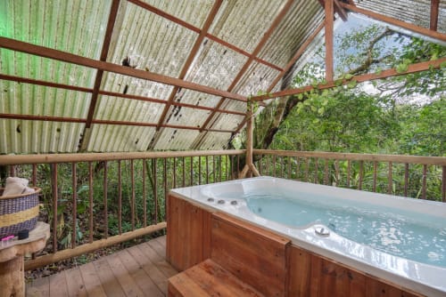 Bañera de hidromasaje en terraza de madera con pérgola en Sukha Glamping, Ríonegro, rodeada de exuberante naturaleza