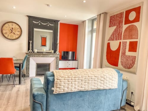 Appartement moderne à La Demeure des Cyprès à Alençon avec canapé bleu, accents rouges, cheminée et décoration contemporaine