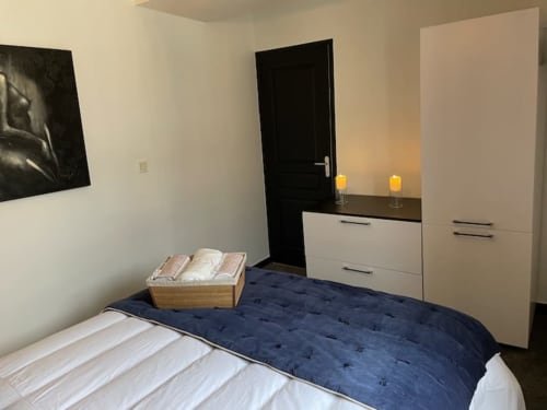 Chambre moderne à La Demeure des Cyprès à Alençon avec literie bleu marine, mobilier blanc et décoration minimaliste