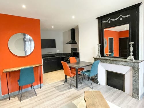 Appartement moderne à La Demeure des Cyprès à Alençon avec murs accentués orange, cuisine noire et salle à manger contemporaine