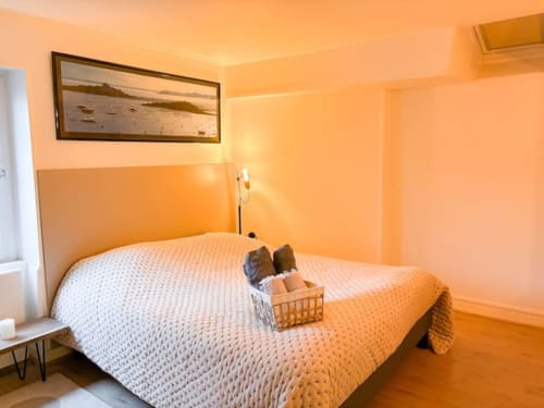 Chambre lumineuse aux murs orange vif à La Demeure des Cyprès à Alençon, lit blanc et décor côtier encadré