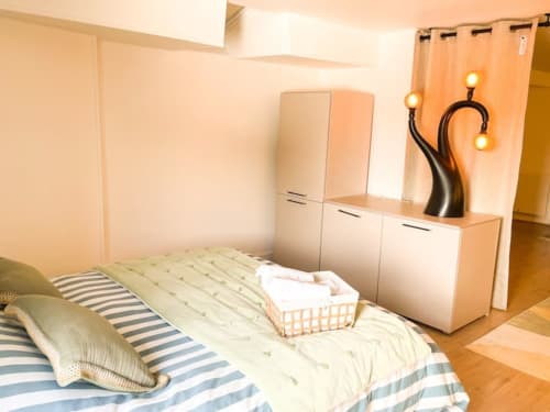 Chambre moderne à l'appartement La Demeure des Cyprès à Alençon avec literie rayée, mobilier minimaliste et ambiance apaisante