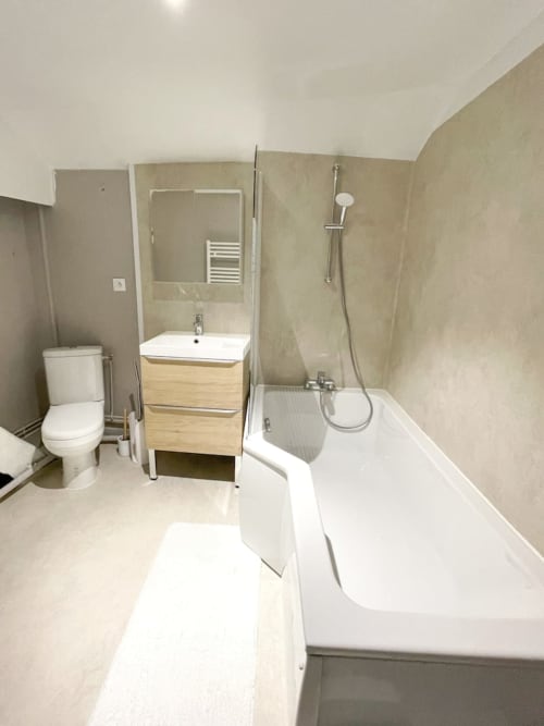 Salle de bain moderne de l'appartement La Demeure des Cyprès à Alençon avec baignoire, douche, lavabo et toilettes