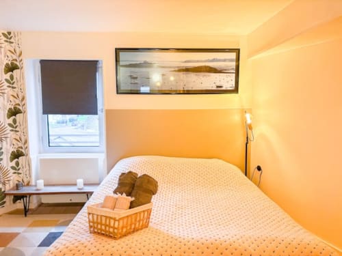 Chambre jaune éclatante à La Demeure des Cyprès à Alençon avec lit moderne et œuvre d'art paysage côtier