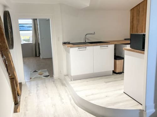 Cuisine moderne de l'appartement La Demeure des Cyprès à Alençon avec vue mer, mobilier blanc et finitions bois clair