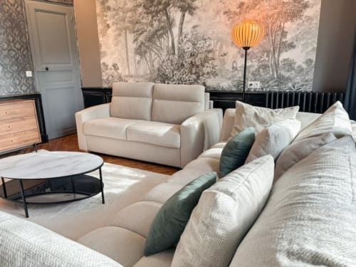 Élégant salon d'appartement de luxe à La Demeure des Cyprès avec sièges crème, papier peint forestier et mobilier contemporain
