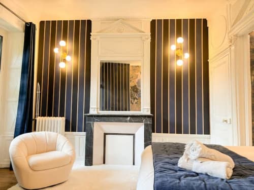 Chambre luxueuse à La Demeure des Cyprès à Alençon avec cheminée, panneaux striés et mobilier contemporain