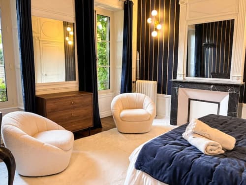 Chambre de luxe à La Demeure des Cyprès à Alençon avec fauteuils crème, lit king size et coiffeuse moderne