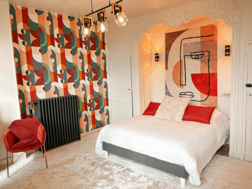Chambre moderne colorée à La Demeure des Cyprès à Alençon avec œuvres géométriques, accents rouges et luminaires suspendus