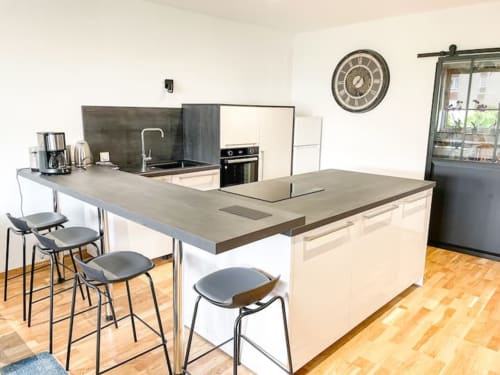 Cuisine moderne avec îlot, sièges de bar et coin repas à l'appartement La Demeure des Cyprès à Alençon