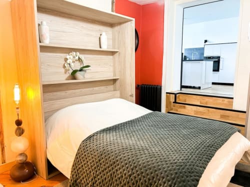 Chambre moderne à La Demeure des Cyprès à Alençon avec tête de lit en bois, literie grise et vue sur la kitchenette