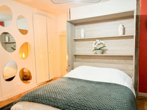 Chambre moderne à La Demeure des Cyprès, Alençon avec literie verte, tête de lit avec étagères bois et miroirs décoratifs