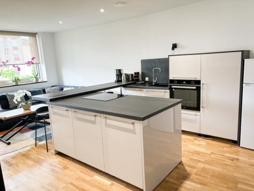 Cuisine moderne avec îlot à l'appartement La Demeure des Cyprès à Alençon, mobilier blanc et parquet
