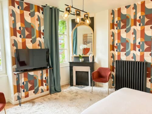 Chambre moderne de La Demeure des Cyprès à Alençon avec papier peint géométrique, TV, miroir de coiffeuse et vue sur jardin