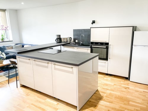 Cuisine moderne avec îlot à l'Appartement La Demeure des Cyprès, Alençon, avec armoires crème et plan de travail foncé