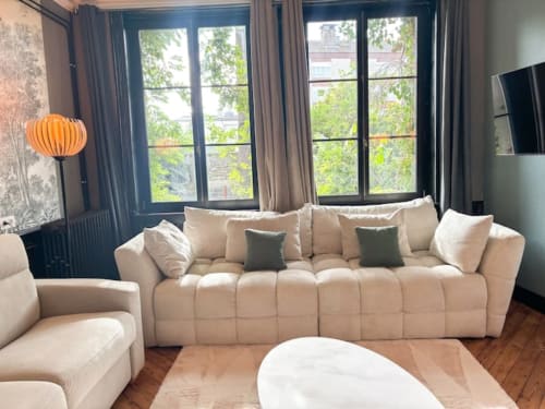 Élégant canapé-lit beige aux accents verts dans une chambre de l'hôtel La Demeure des Cyprès à Alençon, France