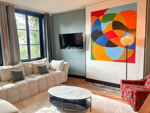 Salon moderne de l'hôtel La Demeure des Cyprès à Alençon avec canapé crème, art abstrait coloré et table basse en marbre