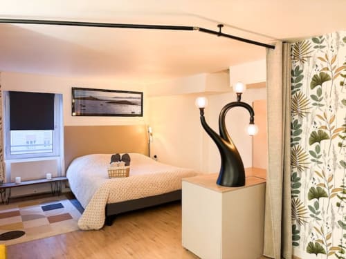 Chambre moderne de l'hôtel La Demeure des Cyprès à Alençon avec lit, rideaux botaniques et lampadaire noir contemporain