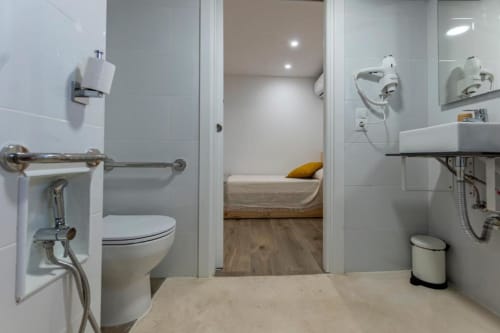 Baño moderno con inodoro, lavabo y zona de ducha en la habitación triple Cal Xot, Poble Nou del Delta