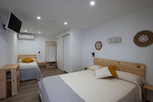 Habitación triple en Cal Xot B&B de Poble Nou del Delta con dos camas de madera, paredes blancas, decoración tejida y comodidades modernas