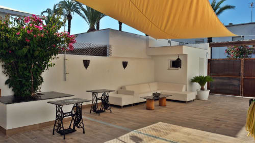 Terraza en la azotea de Cal Xot con asientos, vela de sombra amarilla, palmeras y flores en Poble Nou del Delta