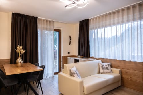 Zona living moderna della Enro Mountain Vacation Home a Roccaraso con divano beige, tavolo in legno e vista montagna