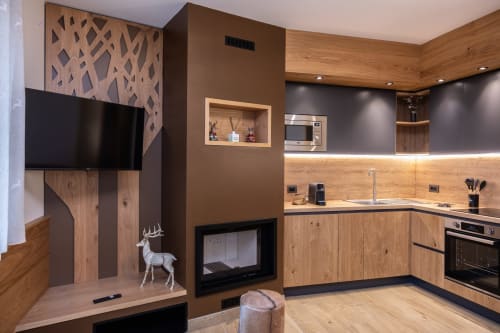 Cucina moderna in legno con camino, TV e dettagli in pietra nell'appartamento Cervo Reale di Enro Mountain Vacation Home