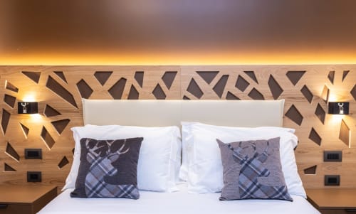 Camera da letto lussuosa presso Enro Mountain Vacation Home a Roccaraso con testata geometrica in legno, cuscini scozzesi e illuminazione ambientale