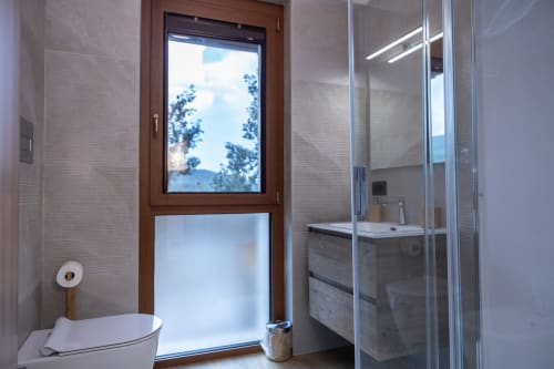 Bagno moderno nella Vacanza Montagna Enro a Roccaraso con porta in legno, cabina doccia in vetro e vista montagna