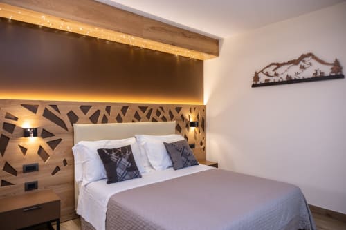 Camera moderna all'Enro Mountain Vacation Home a Roccaraso con testata in legno geometrico, illuminazione d'atmosfera e vista montagna