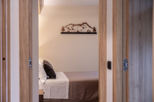 Ingresso della camera da letto di Enro Mountain Vacation Home a Roccaraso con letto e murale con paesaggio montano