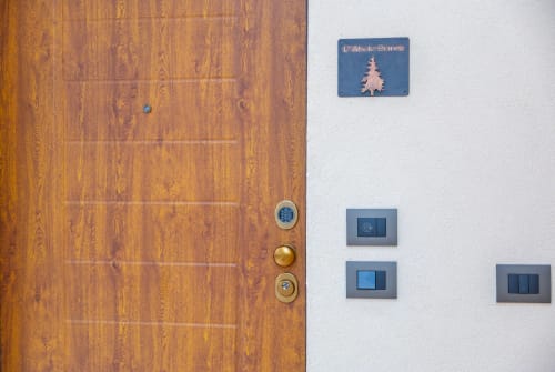 Ingresso dell'appartamento Abete Bianco presso la Casa Vacanze Enro Mountain a Roccaraso, con porta in legno e parete bianca illuminata