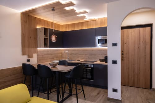 Cucina moderna nella Casa Vacanza Enro Mountain, Roccaraso con mobili neri, dettagli in legno e bancone con tavolo