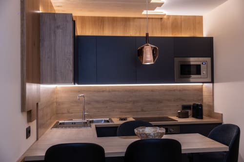 Cucina moderna nell'appartamento Enro Mountain Vacation Home con mobili scuri, rivestimento in legno, lampade a sospensione e zona pranzo