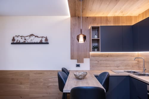 Moderna cucina e zona pranzo di Enro Mountain Vacation Home a Roccaraso con dettagli in legno e arte murale di montagna