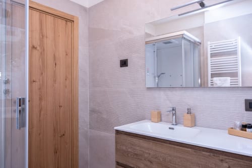 Bagno moderno nella Vacation Home Enro di Roccaraso con porta in legno, rivestimento in piastrelle bianche e lavabo