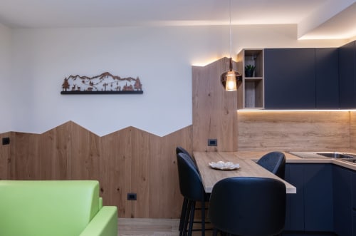 Cucina e zona pranzo moderna presso l'Enro Mountain Vacation Home a Roccaraso con arte tematica montana e sedute verdi