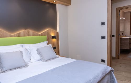 Camera moderna a Enro Mountain Vacation Home a Roccaraso con testiera verde, dettagli in legno e bagno ensuite