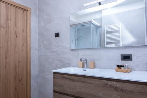 Moderno bagno dell'appartamento Stella Alpina presso Enro Mountain Vacation Home a Roccaraso, con mobile in legno, lavabo bianco e