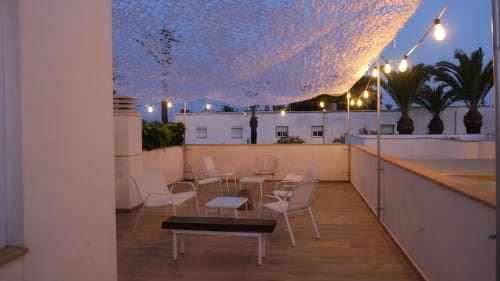 Terraza en azotea de Cal Xot al atardecer con zona de estar, luces colgantes y palmeras en Poble Nou del Delta