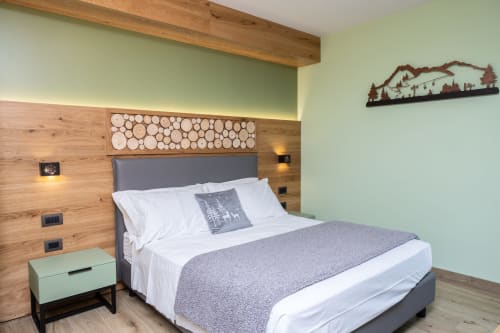 Camera da letto moderna con testata in legno, pareti verde menta e decorazioni montane presso Enro Mountain Vacation Home a Roccaraso