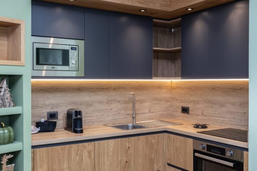 Cucina moderna nella Vacation Home Enro Mountain a Roccaraso con piano in legno, cabinetry blu navy e acciaio inox