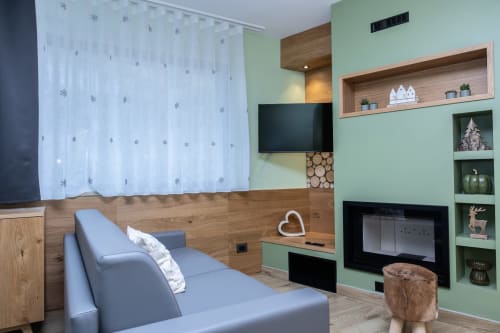 Camera da letto moderna nella Enro Mountain Vacation Home di Roccaraso con letto grigio, parete accent verde menta, camino e