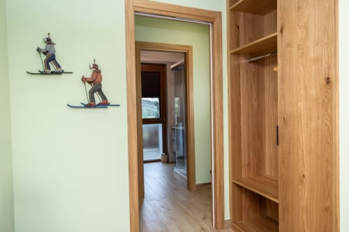 Corridoio con pareti verde chiaro, porte in legno e scaffali presso la Casa Vacanze Enro Mountain, Roccaraso