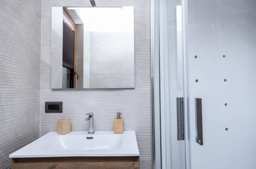 Moderno bagno della Casa Vacanze Enro Mountain a Roccaraso con piastrelle bianche, lavabo sospeso e doccia in vetro