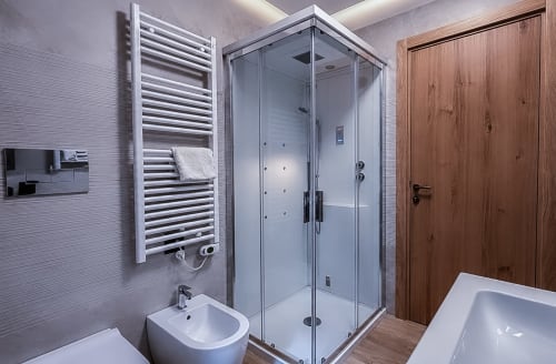 Bagno moderno con doccia in vetro, scaldasalviette bianco, bidet e porta in legno presso l'Enro Mountain Vacation Home