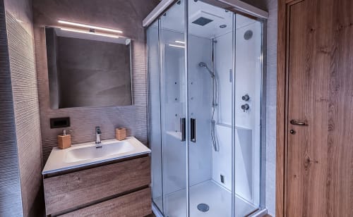 Bagno moderno della Vacanze Enro Mountain a Roccaraso con doccia in vetro, lavabo design e dettagli in legno