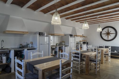 Cocina y comedor integrados en Cal Xot B&B en Poble Nou del Delta con vigas de madera, lámparas colgantes y estilo rústico